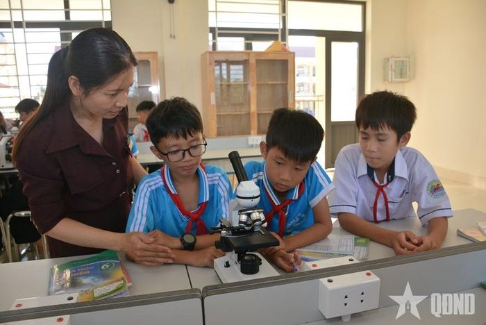 Các em nhỏ rất thích thú khi được làm quen với kính hiển vi quang học.