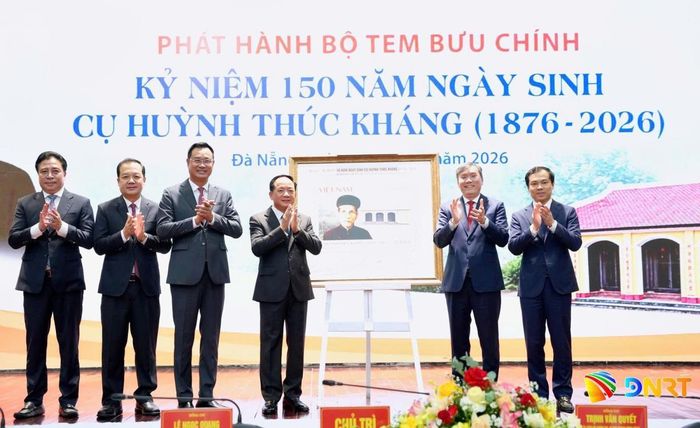 Các đại biểu chụp ảnh lưu niệm với tranh tem kỷ niệm 150 năm ngày sinh cụ Huỳnh Thúc Kháng.