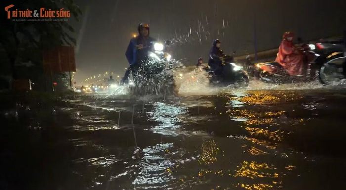 Người dân khốn đốn trong cảnh trên trời mưa xối xả; dưới mặt đường nước ngập lênh láng.
