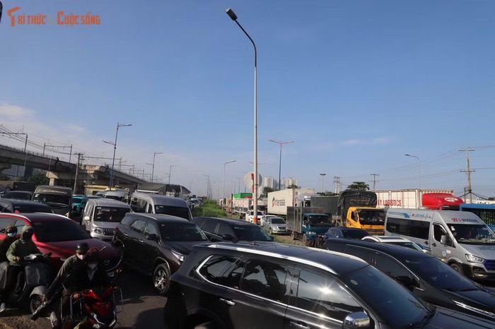 Người đi xe máy chật vật tìm đường thoát giữa dòng ô tô và xe tải nối dài.