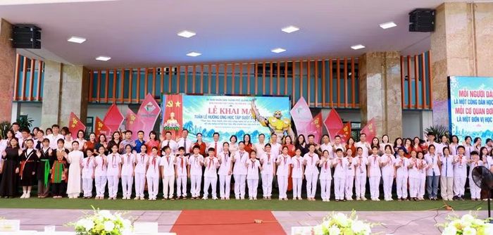 Các đại biểu và các em học sinh chụp ảnh lưu niệm.