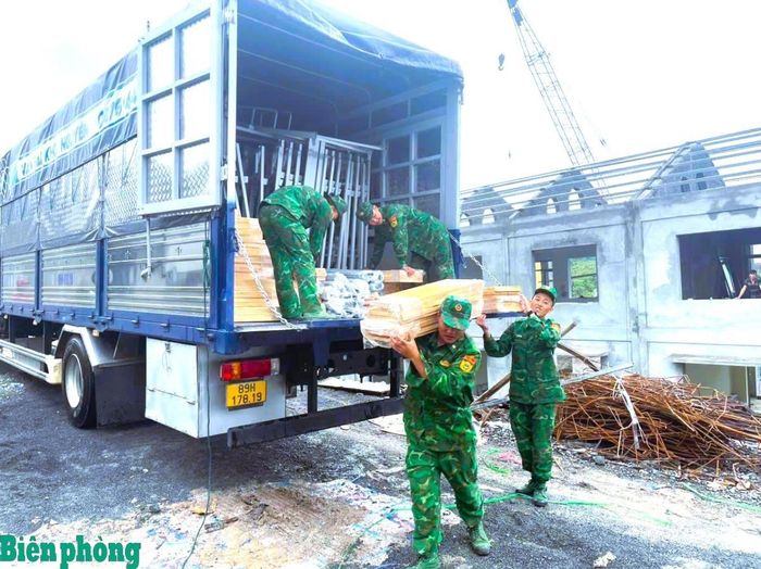 Cán bộ, chiến sĩ Đồn Biên phòng cửa khẩu Săm Pun, Bộ đội Biên phòng tỉnh Tuyên Quang tham gia vận chuyển và lắp đặt trang thiết bị tại Trường Phổ thông nội trú liên cấp Tiểu học và Trung học cơ sở Sơn Vĩ. Ảnh: Hoàng Chính