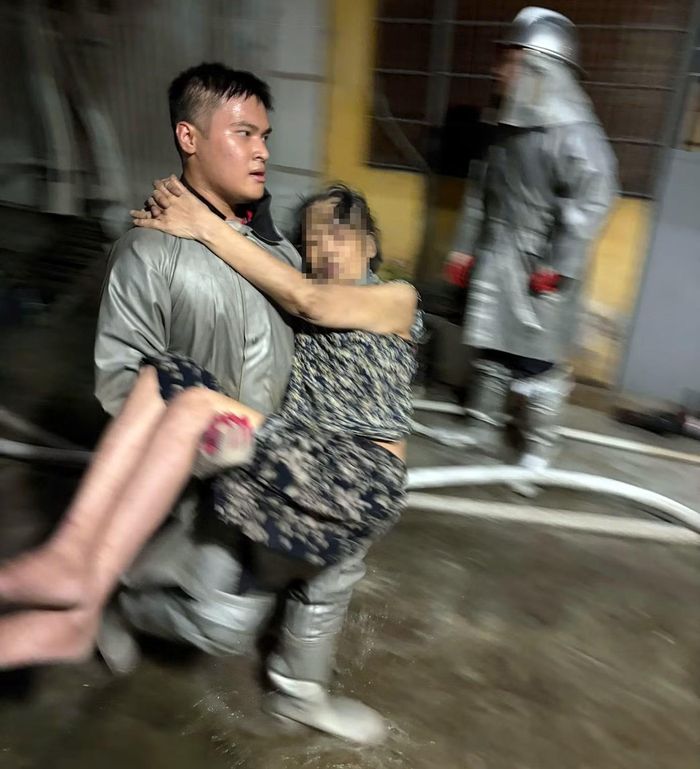 Hạ sĩ Hoàng Hải Long bế nạn nhân từ trong ngôi nhà bị cháy trên phố Đội Nhân ra ngoài.