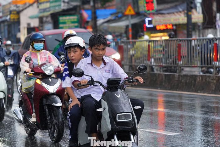 Do khu vực gần trường học, nhiều học sinh đội mưa trở về nhà.