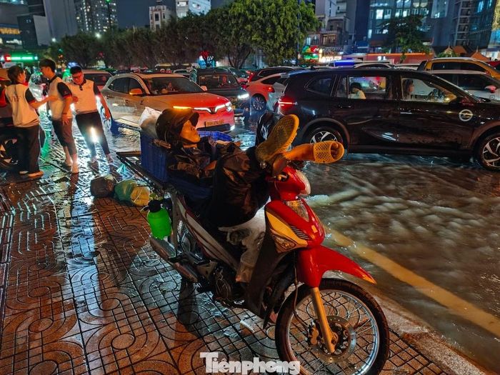 Đường ngập, kẹt xe, anh P.T (ngụ phường Long Bình) dựng xe bên đường chờ nước rút để về nhà. Ảnh: Khoa Nam