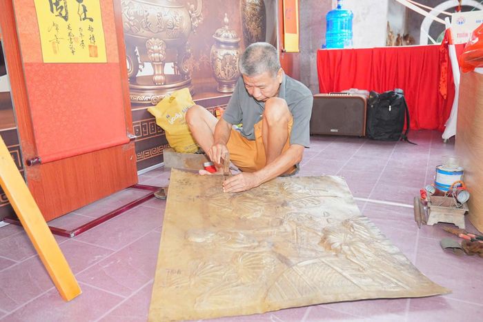 Nghệ nhân thúc đồng mỹ thuật thao tác tạo hình tranh đồng tại không gian lễ hội, mang đến cho du khách trải nghiệm trực tiếp về một nghề thủ công truyền thống
