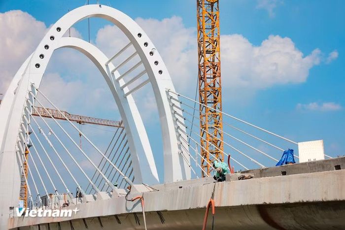 Sau hợp long, các hạng mục hoàn thiện như lan can, bê tông nhựa mặt cầu đang tiếp tục được nhà thầu tăng tốc triển khai. (Ảnh: Hoài Nam/Vietnam+)
