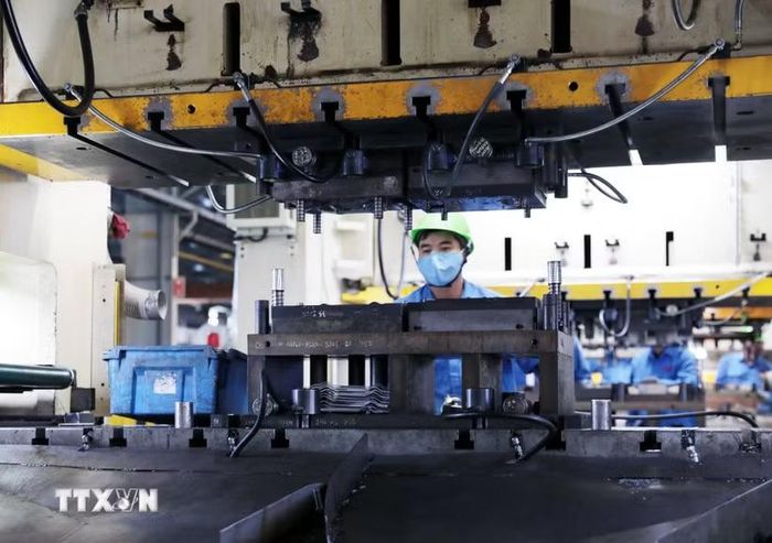 Công nhân Công ty Trách nhiệm hữu hạn Công nghệ Cosmot 1 (Phú Thọ) vận hành dây chuyền sản xuất. (Ảnh: Tạ Toàn/TTXVN)