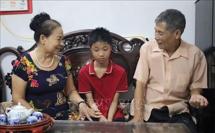 Bà Nguyễn Thị Nghi động viên em Trần Đăng Phúc, học sinh có hoàn cảnh khó khăn ở địa phương, vươn lên trong học tập.