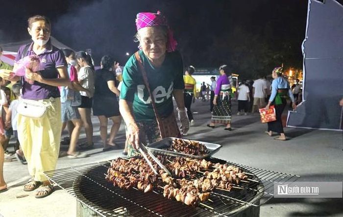 Bà Hà Thị Em nướng thịt lợn mán phục vụ du khách tại đêm khai mạc Phiên chợ vùng cao.
