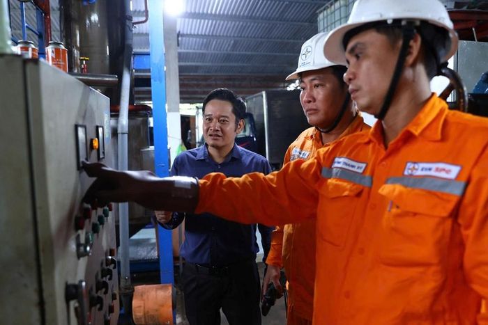 Công nhân ngành điện đang chia sẻ việc sử dụng thiết bị điện tại xưởng làm đá của Công ty TNHH TK55. Ảnh: Huy Hùng - TTXVN
