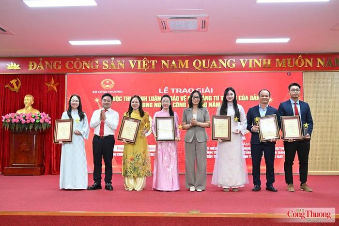 Đồng chí Hà Thị Trang - Phó Trưởng Ban thường trực, Ban Tuyên giáo và Dân vận Đảng ủy Chính phủ (thứ 5 từ trái sang) và đồng chí Nguyễn Văn Minh - Ủy viên Ban Chấp hành Đảng bộ Bộ Công Thương, Tổng Biên tập Báo Công Thương, Phó Trưởng ban Tổ chức cuộc thi (thứ 2 từ trái sang) trao giải Ba cho các tác giả, nhóm tác giả đoạt giải. 