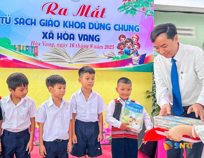 Chủ tịch UBND xã Hòa Vang Lê Phú Nguyện trao sách cho học sinh tại chương trình ra mắt Tủ sách giáo khoa dùng chung. Ảnh: SANG THU