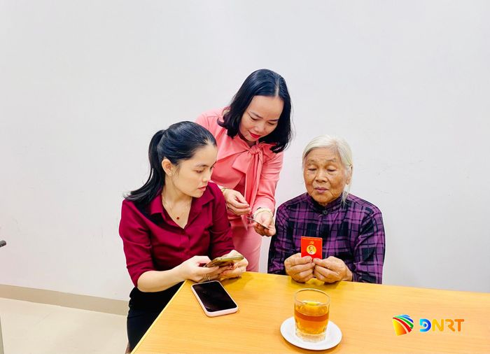 Cán bộ hỗ trợ đảng viên lớn tuổi cài đặt ứng dụng. Ảnh: HỒNG LÊ