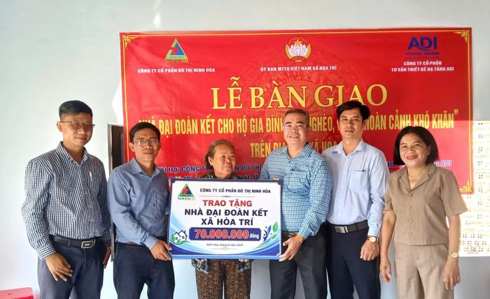 Lãnh đạo xã Hòa Trí và nhà tài trợ trao bảng tượng trưng căn nhà cho bà Nguyễn Thị Hiền.