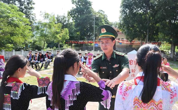 Cán bộ Bộ đội Biên phòng tận tình chỉnh bàn tay, tư thế chào cho học sinh.