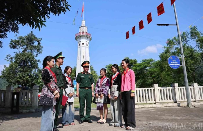 Dưới cột cờ Lũng Pô, cán bộ Bộ đội Biên phòng trò chuyện cùng học sinh trong buổi học ngoại khóa.