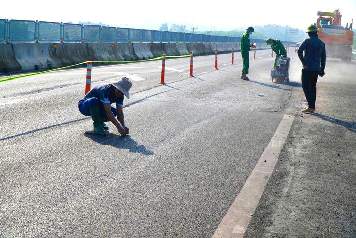 Ngay từ sáng sớm, trên phần đường cần sửa chữa, máy móc chuyên dụng liên tục được đưa vào vị trí. Công nhân chia thành nhiều nhóm, khẩn trương cắt, bóc lớp bê tông nhựa hiện hữu tại những vị trí xuất hiện vết nứt.
