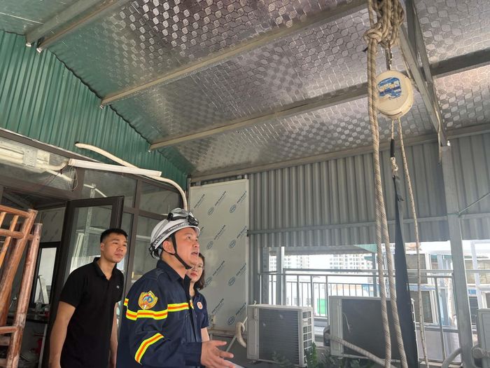 Ông Nguyễn Duy Thanh (áo đen) được hướng dẫn lắp đặt và sử dụng hệ thống thoát hiểm trên sân thượng nhà mình. Ảnh: Bảo Hân