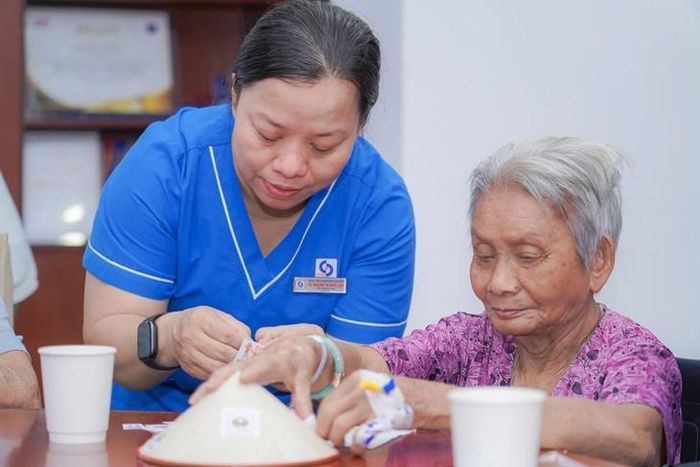 Nhân viên bệnh viện hỗ trợ bệnh nhân trang trí nón lá. Ảnh: BV cung cấp