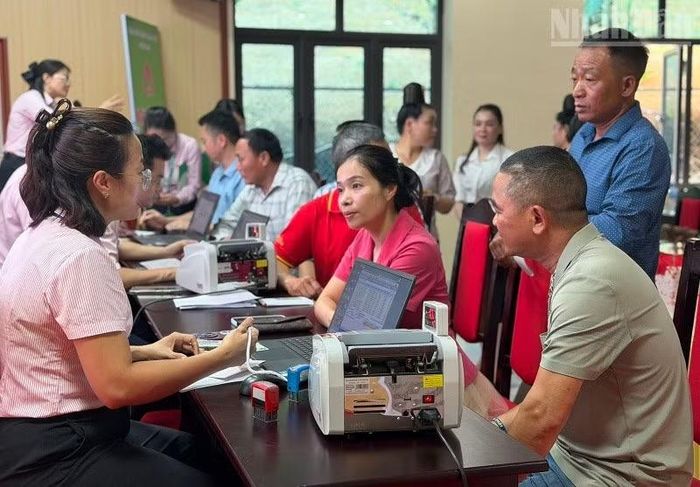 Cán bộ tín dụng Phòng Giao dịch Ngân hàng Chính sách xã hội Mường Ảng (tỉnh Điện Biên) hướng dẫn cán bộ, nhân dân xã Búng Lao làm thủ tục mở sổ tiết kiệm để hỗ trợ người nghèo vay vốn. (Ảnh: LÊ LAN)