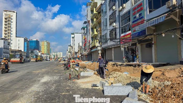 Phần đường chính đã thông xe, trong khi công nhân tiếp tục thi công vỉa hè, lát đá và hoàn thiện các hạng mục trước dãy cửa hàng hai bên tuyến.