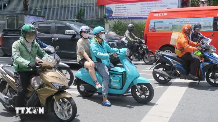 Tài xế công nghệ làm việc dưới thời tiết nắng nóng. (Ảnh: Đinh Hằng/TTXVN)