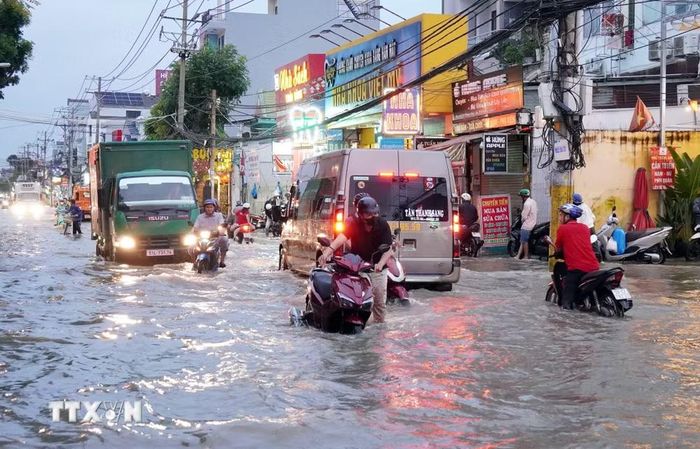 Người dân di chuyển khó khăn trên đường Phạm Hữu Lầu, phường Tân Mỹ do triều cường dâng cao, ngày 6/11/2025. (Ảnh: Trung Tuyến/TTXVN)