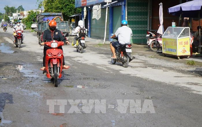 Nhiều hộ dân ở ven đường ĐT-865 sống trong cảnh nắng bụi, mưa bùn lầy. Ảnh: Nhựt An - TTXVN