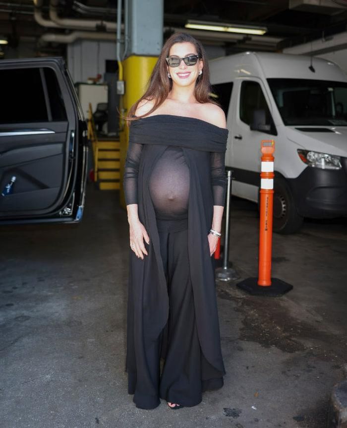 Anne Hathaway xuất hiện tại chương trình The Drew Barrymore Show trong một chiếc váy đen dáng mềm mại, trễ vai, với các chi tiết draping và phần thân trên bán xuyên thấu. Ảnh: Getty Images