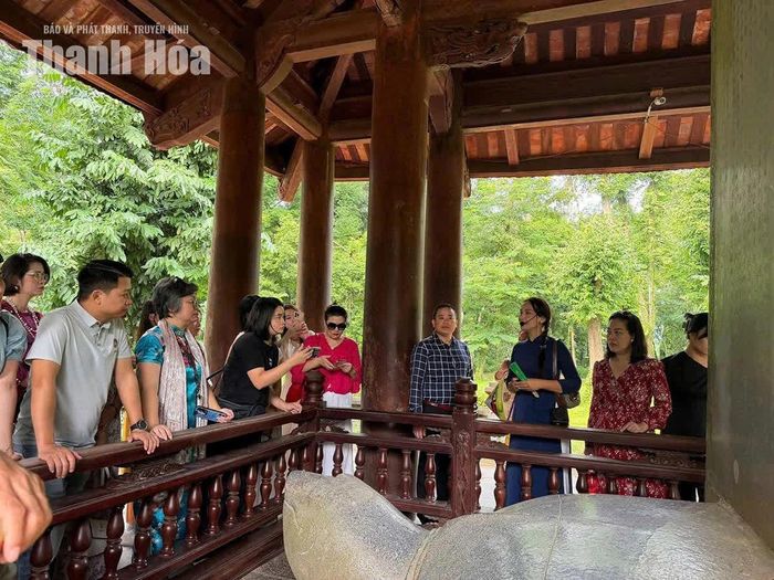 Du khách chăm chú nghe chị Hoàng Thị Hiền thuyết minh tại Nhà bia Vĩnh Lăng thuộc Khu Di tích quốc gia đặc biệt Lam Kinh.
