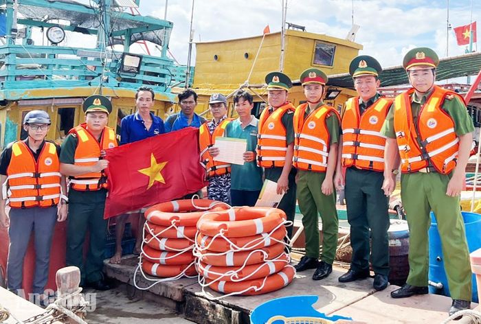 Cán bộ Đồn Biên phòng Xẻo Nhàu cùng lực lượng công an tặng cờ Tổ quốc cho ngư dân và tuyên truyền, vận động ngư dân chấp hành quy định về khai thác hải sản. Ảnh: ÚT CHUYỀN