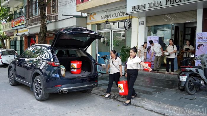 Các thành viên trong nhóm Thiện nguyện Bồ Đề Tâm chuyển những suất cháo lên xe đưa đến Trung tâm Y tế khu vực Bát Xát.