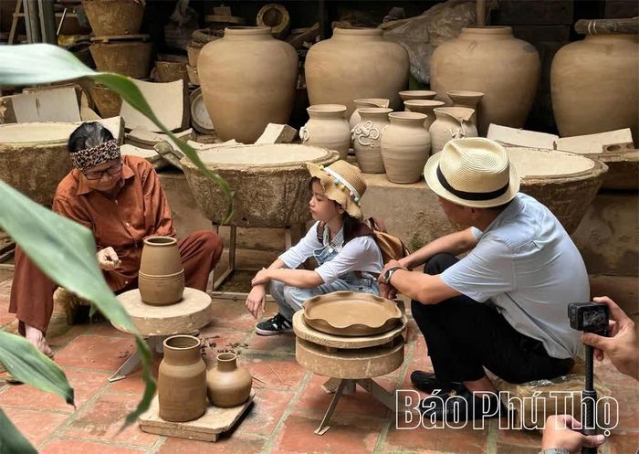 Nghệ nhân Giang Thị Nhạn (trái) chia sẻ kinh nghiệm làm gốm sành truyền thống cho du khách.