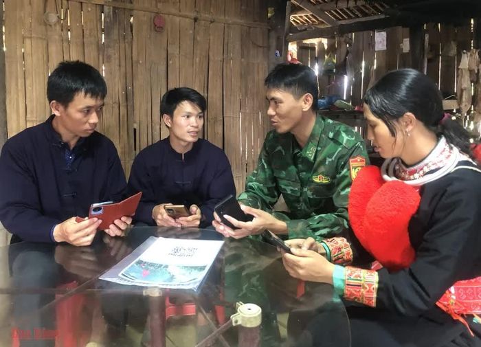 Chảo A Nảy (giữa) cùng cán bộ biên phòng hướng dẫn người dân Mác Nẻng quét mã QR, tra cứu thông tin pháp luật trên điện thoại thông minh.