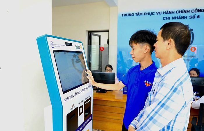 Đoàn viên thanh niên hỗ trợ người dân thực hiện dịch vụ công trực tuyến tại Trung tâm Phục vụ hành chính công thành phố Hà Nội - Chi nhánh số 8. Ảnh: Phạm Hùng