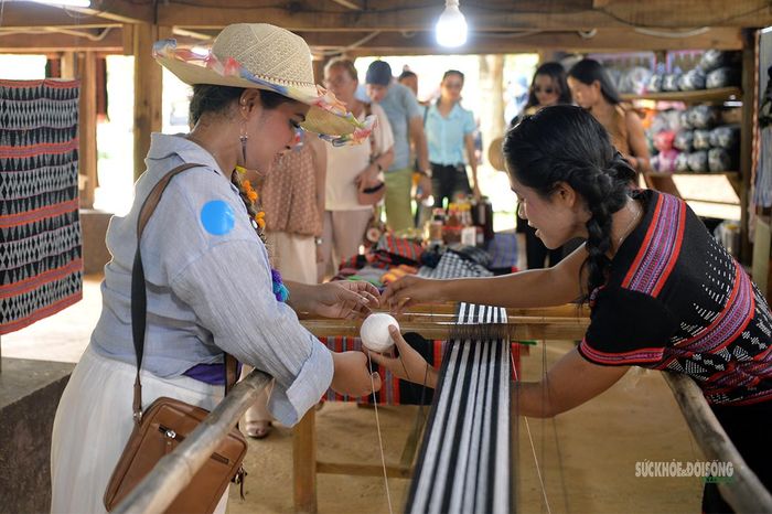 Du khách quốc tế tìm hiểu cách đưa sợi, thao tác trên khung dệt cùng nghệ nhân. Ảnh: Tuấn Anh