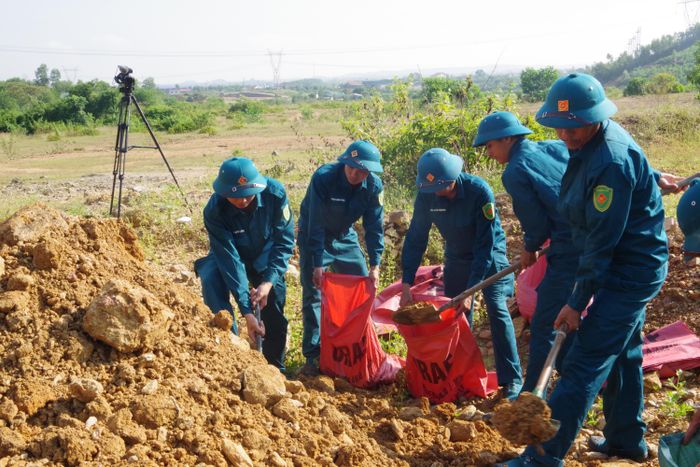  Lực lượng dân quân tự vệ tham gia đóng gói đất cát để phục vụ công tác hủy nổ. Ảnh: TRỌNG SƠN 