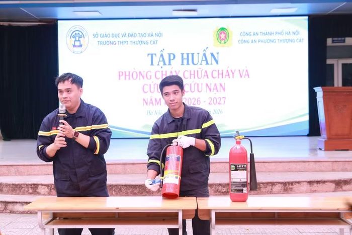 Thiếu tá Vũ Việt Dũng (trái) giới thiệu về hình dạng, tính năng và cách thức sử dụng bình chữa cháy mini cho học sinh.