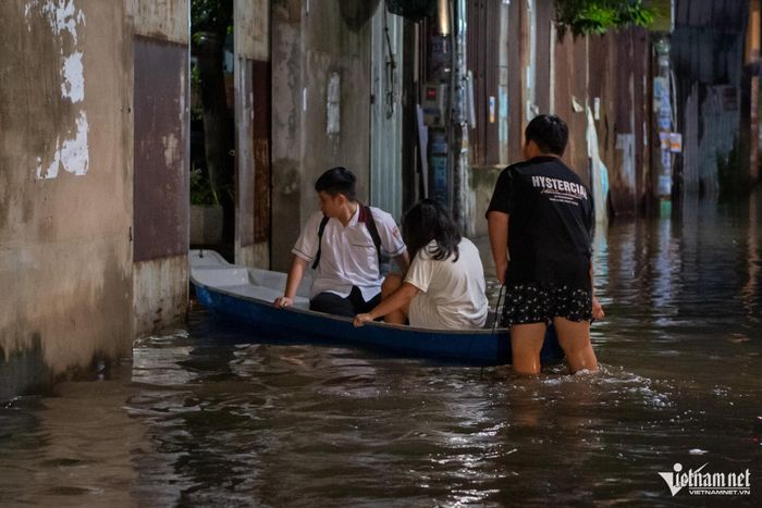 Người thân của bà Phước dùng thuyền hỗ trợ người dân di chuyển qua đoạn hẻm ngập sâu.