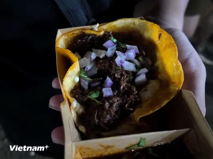 Món taco bò đặc trưng từ quầy Mexico với bánh ngô giòn, thịt bò và các loại rau củ (hành tây, ớt chuông) dậy mùi, đi kèm nước sốt riêng. (Ảnh: Minh Anh/Vietnam+)