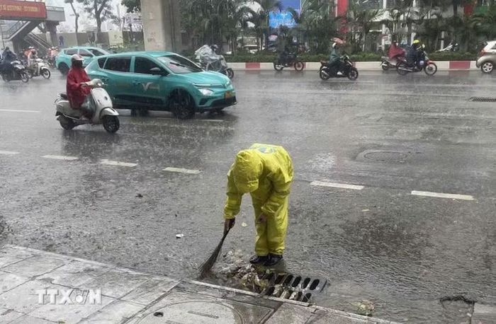 Công nhân công ty thoát nước vớt rác để tiêu thoát nước nhanh. (Ảnh: Nguyễn Thắng/TTXVN)