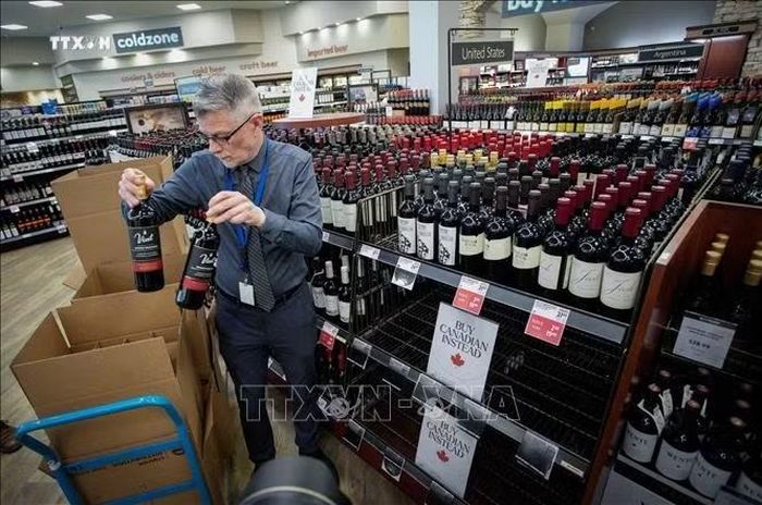Nhân viên dỡ các sản phẩm rượu của Mỹ khỏi kệ tại một cửa hàng ở Vancouver, tỉnh British Columbia, Canada, khi căng thẳng thuế quan diễn ra giữa hai nước. Ảnh: THX/TTXVN phát