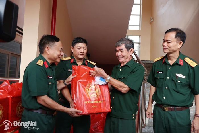 Đại tá Nguyễn Như Trúc, Phó Chủ nhiệm Chính trị Quân khu 7 (bìa trái) tặng quà người có công trong chương trình khám bệnh miễn phí sáng 3-10. Ảnh: Nguyệt Hà