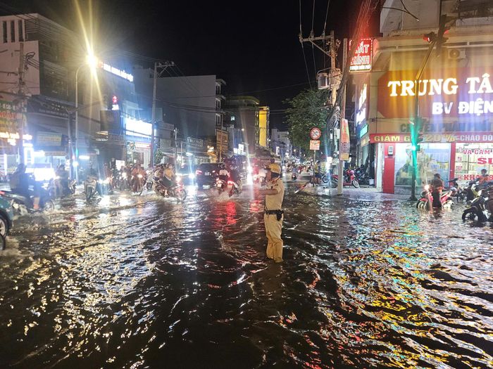 Giữa màn mưa trắng xóa, ánh đèn phương tiện nối dài trong đêm, những chiến sĩ CSGT đứng giữa dòng xe, liên tục quan sát và điều tiết phương tiện. Tại các khu vực ngập nước, lực lượng chức năng phối hợp hỗ trợ, hướng dẫn người dân di chuyển, hạn chế ùn ứ và xử lý những tình huống phát sinh.