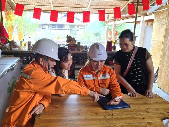 Cán bộ nhân viên Điện lực Hà Giang hướng dẫn người dân cách xem tiền điện trên ứng dụng Chăm sóc khách hàng của ngành Điện. Ảnh NPC