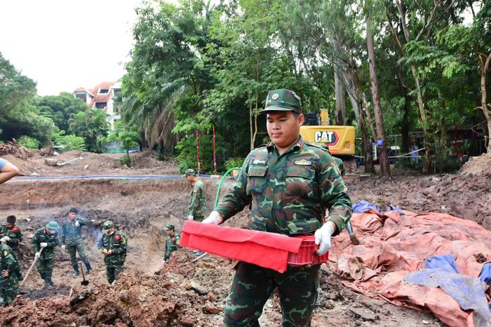 Các chiến sĩ Đội K74 đưa hài cốt liệt sĩ vừa tìm thấy về khu vực lấy mẫu trong Công viên Lê Thị Riêng.