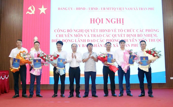 Các đồng chí lãnh đạo xã Trần Phú tặng hoa, trao Quyết định tổ chức lại các phòng chuyên môn thuộc UBND xã. Ảnh: HĐ