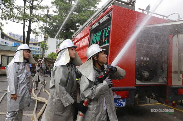 Các chiến sĩ trong trang phục bảo hộ triển khai lăng phun nước. Ảnh: Tuấn Anh
