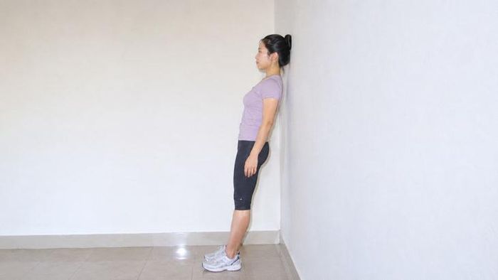 Cách thực hiện bài tập tựa đầu vào tường cải thiện tình trạng gù cổ. Ảnh AI